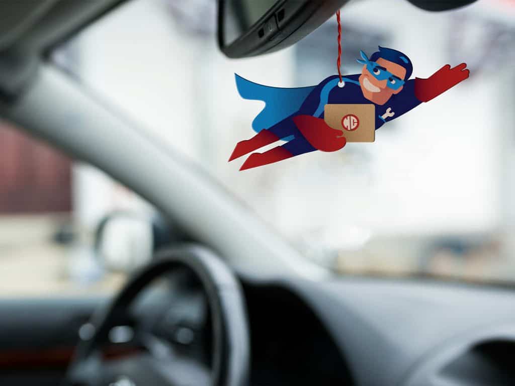 In diesem Bild sieht man wie der "Duft-Hero" von Happy Cars an einem Rückspiegel vom Auto hängt.