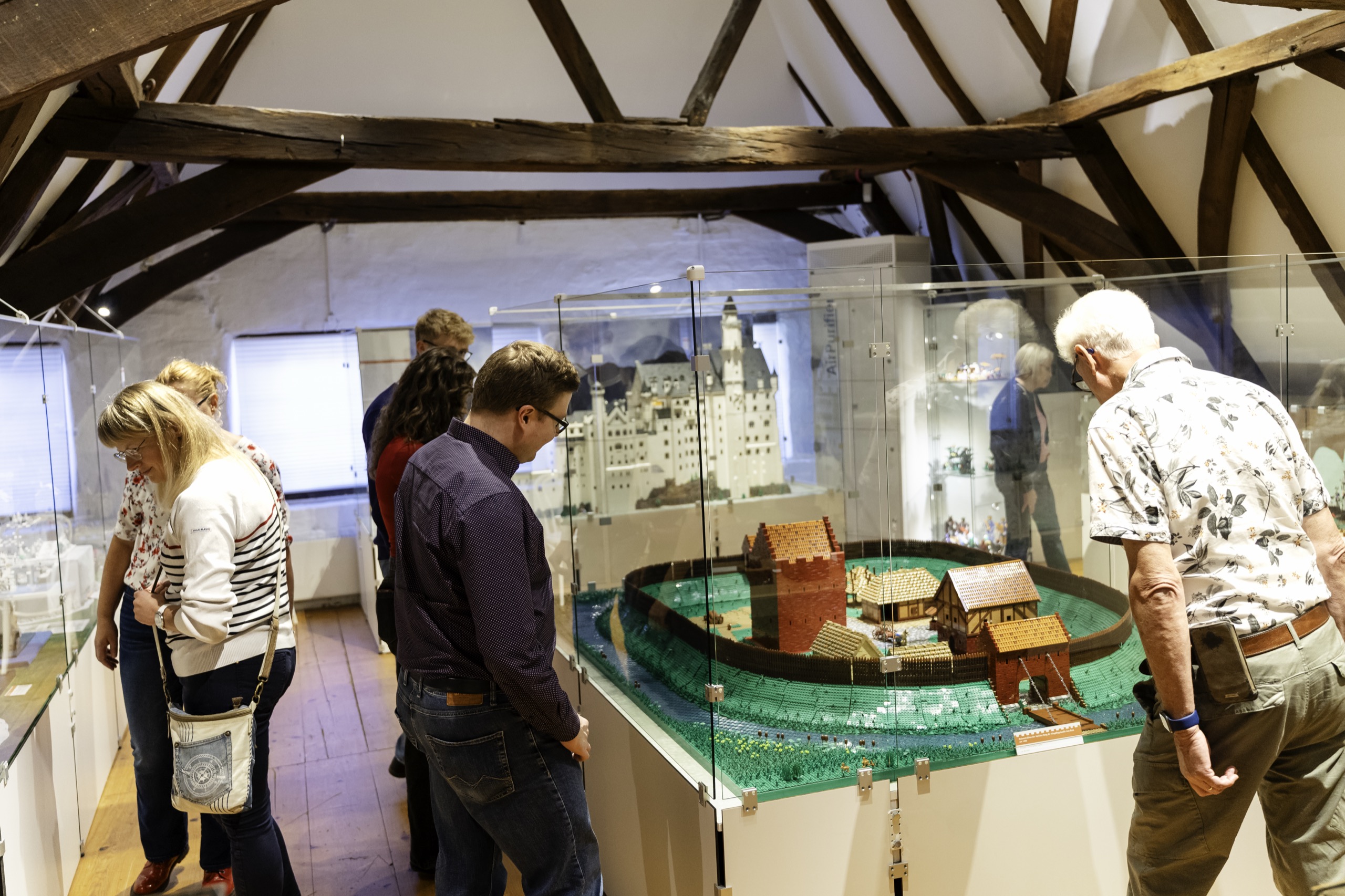 Besucherinnen und Besucher im Historischen Museum Aurich vor den historischen Burg- und Schlossmodellen unter dem Fachwerk-Dachstuhl
