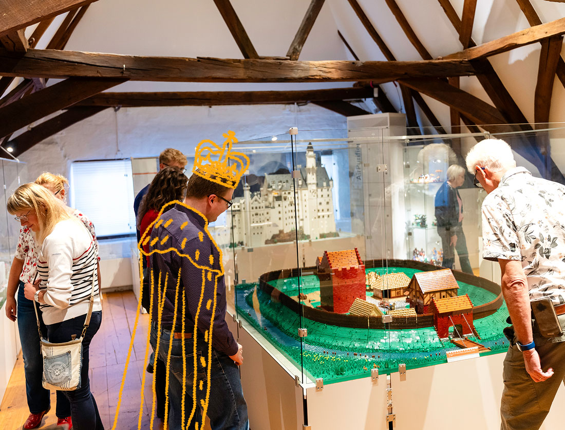 Besucher im Historischen Museum Aurich vor dem Burgmodell mit handgezeichneter goldener Königskrone und Umhang als Brücke zwischen Historie und Gegenwart