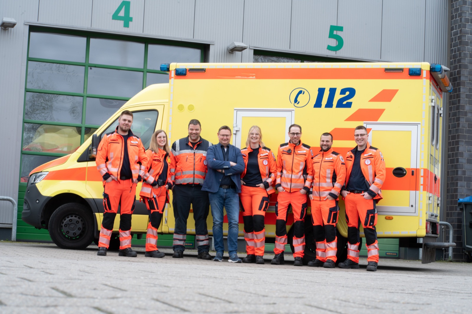 Team des Rettungsdienstes Landkreis Aurich vor Rettungswagen und Fahrzeughalle