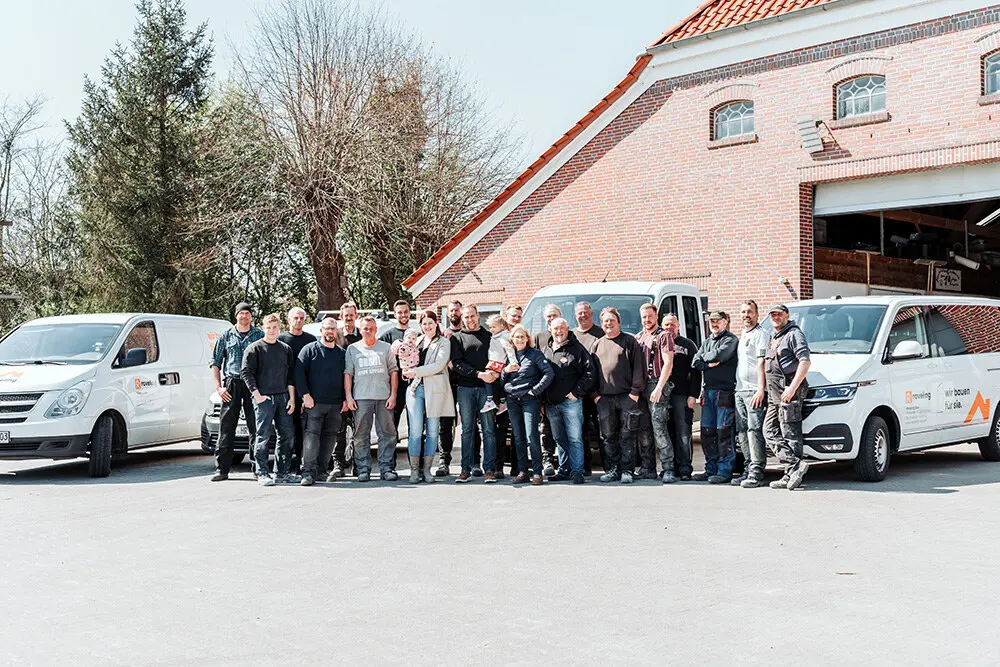 20-köpfiges Team und Familie Raveling vor Klinker-Giebel und Transporterflotte in Ochtelbur